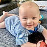baby, blue_striped_clothing, bright, carpet, child, couch, cute, face, hand, happy, home, indoor, infant, lying_down, person, playful, smiling, soft_surface, toy, young_child