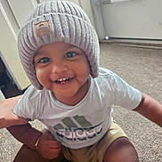 Kenzo joined the competition — help win amazing prizes! apparel, baby, carpet, child, cute, door, face, happy, hat, indoor, knit_hat, person, playful, portrait, shorts, sitting, smiling, toddler, tshirt, young_child