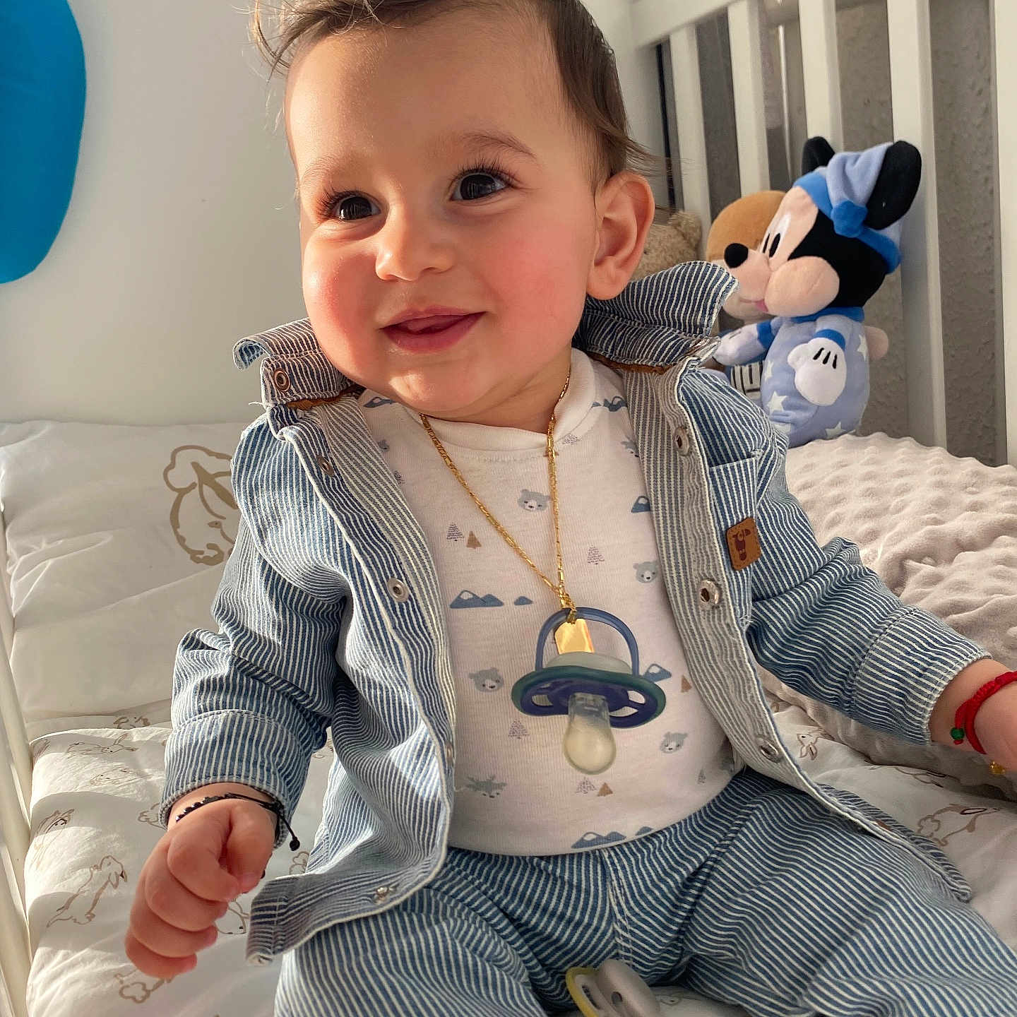 Antonio participe au concours pour gagner de l'argent avec cette photo : baby, bed_sheet, blanket, child, crib, denim_jacket, gold_chain, happy, infant, long_eyelashes, mickey_mouse, nursery, pacifier, pacifier_necklace, plush_toy, rosy_cheeks, sitting, smiling, striped_clothing, toddler