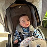 baby, child, stroller, plush_toy, smiling, striped_clothing, seatbelt, sunlight, indoor, happy, person, cute, infant, toy, comfort, canopy, face, head, small_hand, cozy