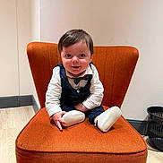 Tiago a rejoint le concours — aidez-le/la à gagner de superbes lots ! baby, infant, child, smile, sitting, orange_chair, chair, bow_tie, vest, white_shirt, socks, footwear, wood_floor, indoor, portrait, happy, hair, face, eyes, basket