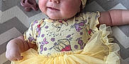 Maple joined the competition — help win amazing prizes! baby, blanket, bow, child, chubby_cheeks, clothing, cute, face, happy, headband, indoors, infant, lying_down, pacifier, patterned_clothes, smiling, soft_fabric, tutu, yellow, zigzag_pattern