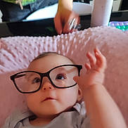 Anastasia a rejoint le concours — aidez-le/la à gagner de superbes lots ! adult_hand, baby, blurred_background, casual, child, clothing, comfortable, couch, curious, expression, face, glasses, hand, indoor, infant, person, pink_blanket, reaching, soft_texture, toy