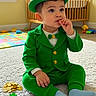 toddler, child, leprechaun_costume, green_suit, green_hat, gold_coins, shamrock, carpet, crib, nursery, toy, play_mat, indoor, cute, sitting, thoughtful, baby, sock, portrait, costume