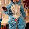 Liam joined the competition — help win amazing prizes! blue_onesie, child, costume, cute, digital_overlay, door, duck_slippers, face, flowers, footwear, holding, indoor, pacifier, pinecone, playful, sitting, table, toddler, vase, yellow_slippers