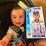 baby, car_seat, toy, smiling, child, infant, colorful, plastic_toy, bobblehead, superman, aaron_judge, baseball, sports_merchandise, happy, cute, indoor, person, clothing, seatbelt, closeup