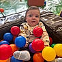 baby, child, play_area, colorful_balls, red_ball, blue_ball, yellow_ball, orange_ball, purple_ball, socks, sitting, cute, indoor, soft_play, toy, infant, portrait, fun, expression, clothing