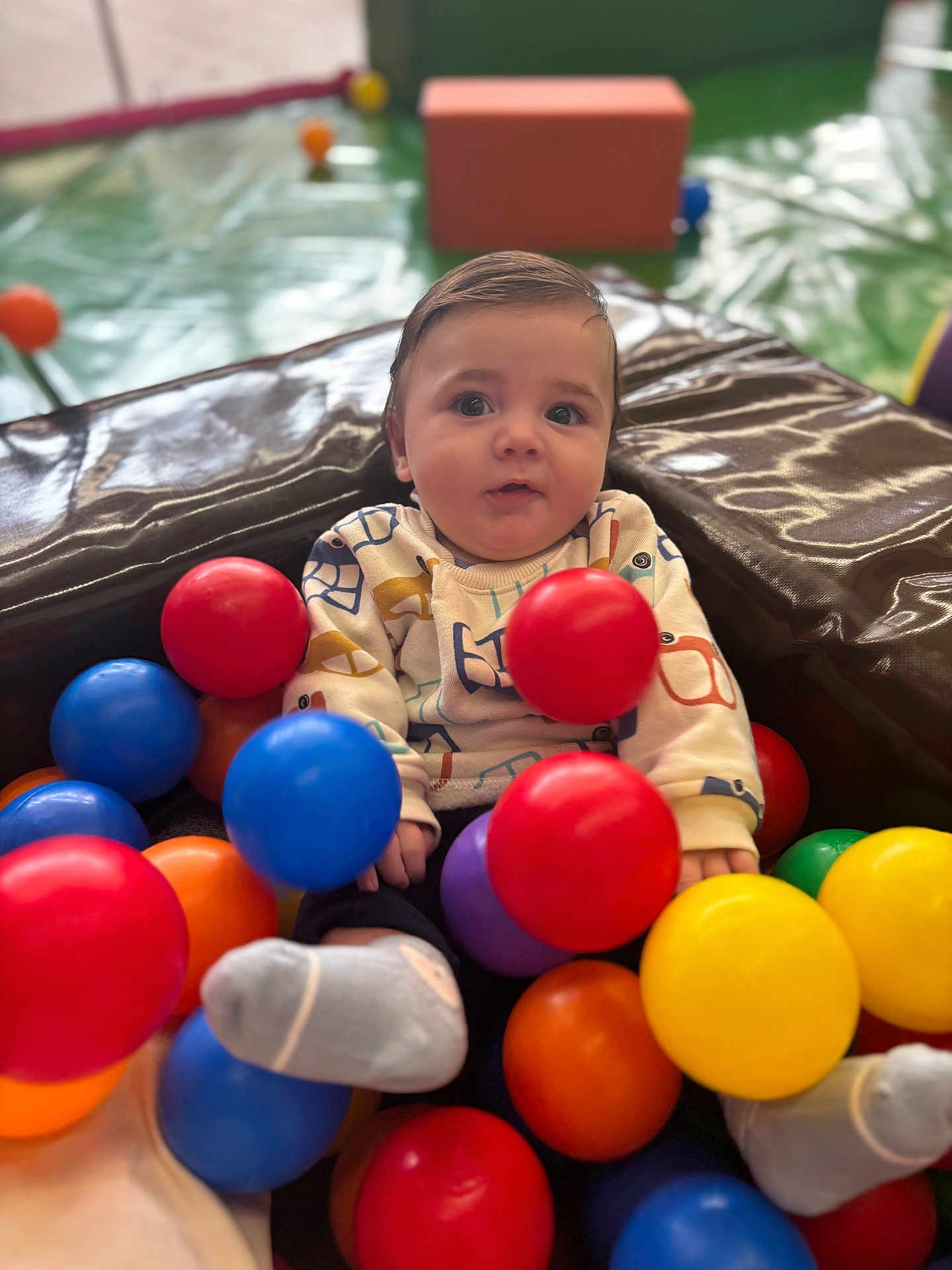 Cali participe au concours pour gagner de l'argent avec cette photo : baby, child, play_area, colorful_balls, red_ball, blue_ball, yellow_ball, orange_ball, purple_ball, socks, sitting, cute, indoor, soft_play, toy, infant, portrait, fun, expression, clothing