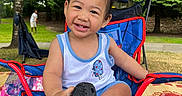 Antonio joined the competition — help win amazing prizes! child, toddler, smiling, outdoor, greenery, trees, chair, red, blue, shoe, sock, grass, mat, person, pigtails, happy, playful, summer, casual_clothing, nature