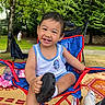 child, toddler, smiling, outdoor, greenery, trees, chair, red, blue, shoe, sock, grass, mat, person, pigtails, happy, playful, summer, casual_clothing, nature