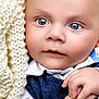 baby, close_up, face, heterochromia, blue_eyes, brown_eyes, knit_blanket, hand, skin, infant, portrait, cute, child, soft_texture, warmth, clothing, newborn, expression, innocence, curiosity