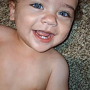Andrew is registered to the contest to win money with this photo: baby, child, smiling, blue_eyes, happy, curly_hair, bare_chest, carpet, person, portrait, cute, infant, human, skin, tongue, teeth, hand, lying_down, playful, closeup