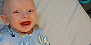 Joseph is registered to the contest to win money with this photo: baby, child, smiling, pajamas, bed, toy, indoor, face, happy, infant, lying, clothing, cute, person, blue, pattern, sleepwear, young, cheerful, background