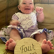 Wisteria joined the competition — help win amazing prizes! baby, brown_couch, celebration, child, couch, cute, feet, four_months, hands, happy, indoor, infant, lace, milestone, person, portrait, purple_clothing, sitting, smiling, wooden_sign
