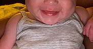 Eloise joined the competition — help win amazing prizes! baby, bedroom, blanket, bottle, child, close_up, couch, cozy, face, happy, indoors, infant, lamp, photography, portrait, sitting, sleeveless_clothing, smiling, striped_onesie, warm_lighting