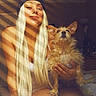 woman, dog, indoor, blonde_hair, beanie, pet, sunlight, shadows, striped_shadows, casual, portrait, smile, long_hair, small_dog, scruffy_dog, bedroom, relaxed, text_overlay, hand_holding_pet, warm_lighting