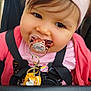 toddler, child, pacifier, headband, pink_clothing, stroller, toy, smiling, face, baby, closeup, seatbelt, cute, infant, person, outdoor, happy, young_child, accessory, portrait