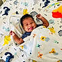 Ja'Rius joined the competition — help win amazing prizes! baby, smiling, blanket, dinosaur, animal_print, infant, lying_down, happy, cozy, cute, child, patterned_sheet, colorful, indoors, playful, soft, warm, toddler, face, raised_arms