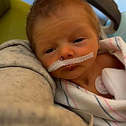 Silas is registered to the contest to win money with this photo: baby, newborn, hospital, blanket, nasal_tube, medical, infant, person, bed, care, resting, wrapped, healthcare, equipment, closeup, face, child, patient, comfort, indoor