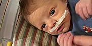 Silas joined the competition — help win amazing prizes! baby, infant, hospital, nasal_tube, medical, bed, cushion, striped, hand, holding, person, healthcare, newborn, clothing, blue_shirt, blanket, portrait, face, lying_down, care