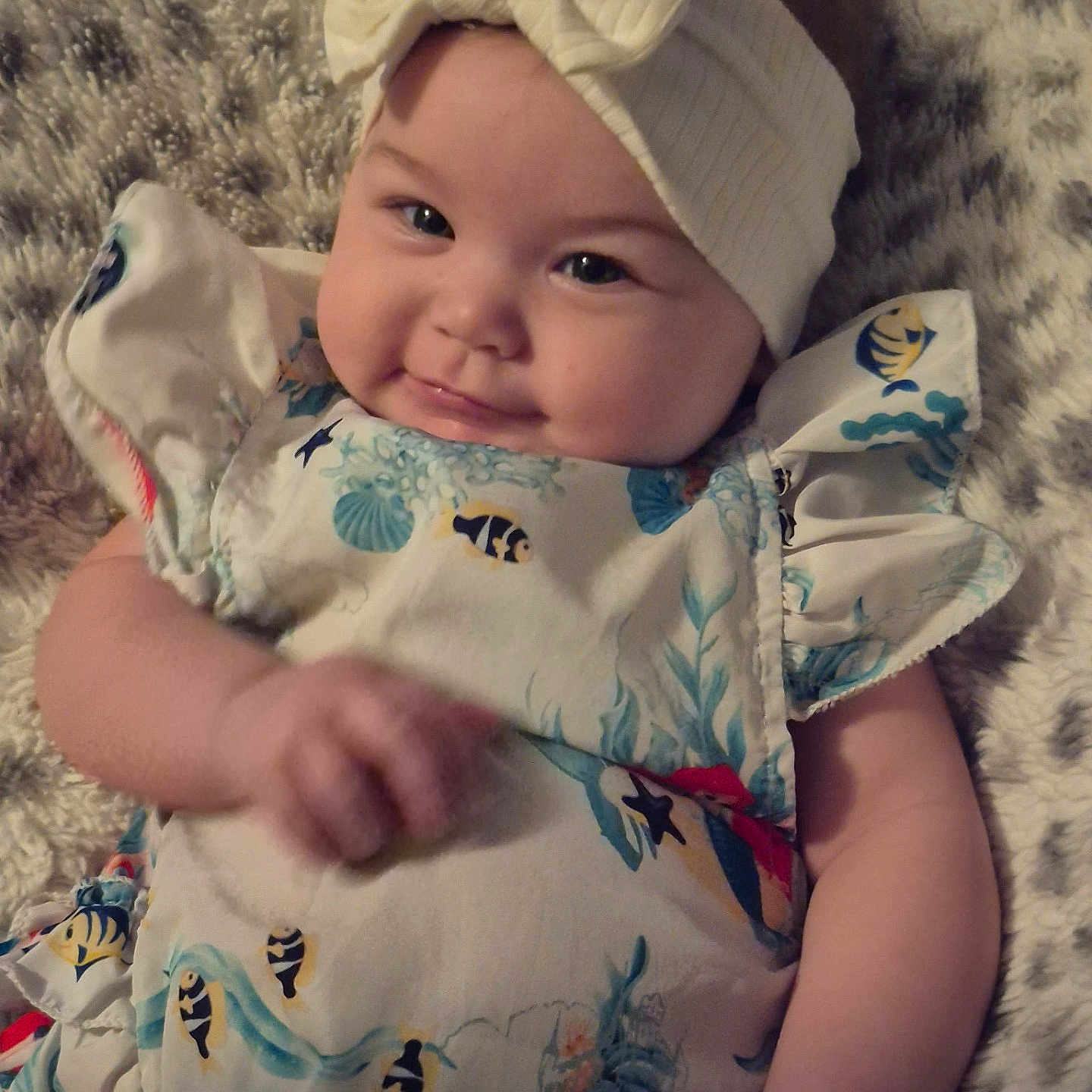 Lucrezia joined the competition — help win amazing prizes! apparel, baby, bow, child, chubby_cheeks, cute, dress, fabric, face, fish_pattern, fluffy_blanket, hand, headband, infant, lying_down, pattern, person, skin, smile, young