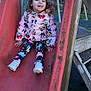child, toddler, slide, playground, playground_equipment, jacket, mickey_mouse, curly_hair, smile, sneakers, outdoor, wood_structure, red_slide, sitting, happy, park, colorful_leggings, shoes, person, playtime