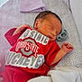 Anthony Allen Pucci is registered to the contest to win money with this photo: newborn, baby, sleeping, onesie, red_clothing, crib, blanket, hat, pacifier, infant, soft_texture, cozy, indoor, resting, cute, peaceful, close_up, face, hand, baby_bedding