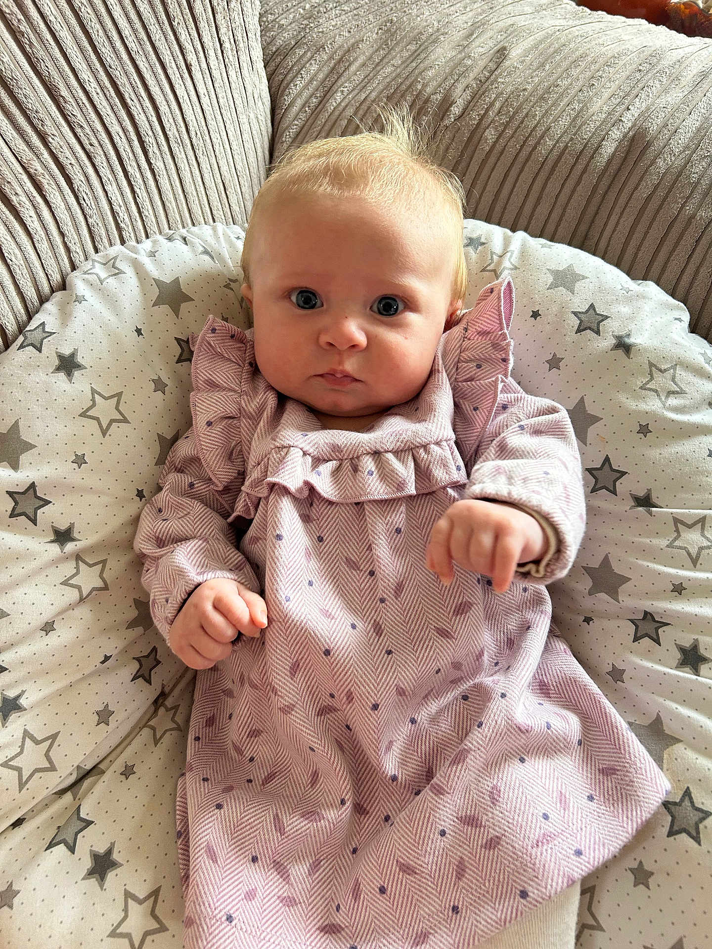 Maeve joined the competition — help win amazing prizes! baby, infant, child, pink_dress, patterned_clothing, cushion, star_pattern, sofa, beige, indoor, portrait, cute, toddler, face, hands, young_child, seated, home, comfort, curious