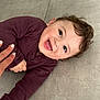 baby, child, smile, happy, floor, tile, hand, clothing, maroon, person, cute, infant, skin, face, eyes, hair, playful, lying_down, indoors, expression