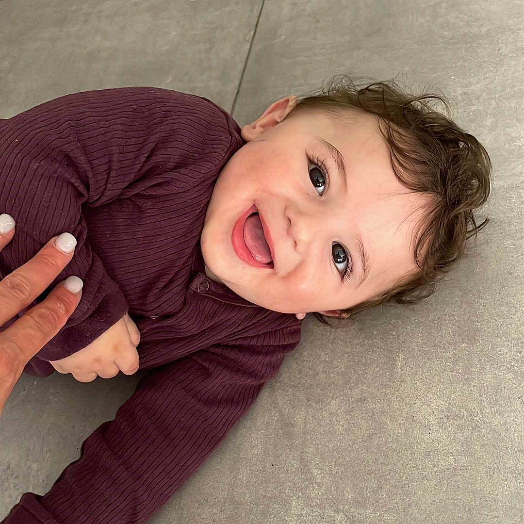 Lyvaï participe au concours pour gagner de l'argent avec cette photo : baby, child, clothing, cute, expression, eyes, face, floor, hair, hand, happy, indoors, infant, lying_down, maroon, person, playful, skin, smile, tile