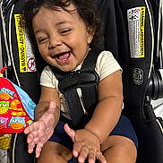 Jace Trinidad joined the competition — help win amazing prizes! baby, child, car_seat, smiling, clapping, curly_hair, infant, toy, happiness, seat_belt, colorful, safety_warning, cute, indoors, happy, person, closeup, infant_clothing, black_hair, playful