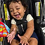 baby, child, car_seat, smiling, clapping, curly_hair, infant, toy, happiness, seat_belt, colorful, safety_warning, cute, indoors, happy, person, closeup, infant_clothing, black_hair, playful