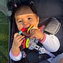 baby, child, stroller, toy, smiling, sunlight, outdoor, happy, infant, face, hands, foot, clothing, seatbelt, safety, pink, colorful, playful, grass, portrait