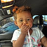 Nova is registered to the contest to win money with this photo: toddler, child, car_interior, curly_hair, white_tshirt, pacifier_clip, seat, window, daylight, hand, face, person, blue_jeans, seatbelt, headrest, car_door, light, indoors, young_child, cute