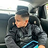 backseat, black_clothing, blue, boy, car, car_seat, child, indoors, looking_away, passenger, portrait, safe, seatbelt, short_hair, sitting, tablet, transportation, travel, vehicle, window