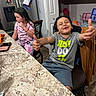 children, boy, girl, smiling, thumbs_up, portrait, indoor, kitchen, table, countertop, refrigerator, groceries, shelves, chair, gray_shirt, pink_pajamas, curly_hair, long_hair, happy, family