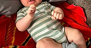 Liam joined the competition — help win amazing prizes! baby, blanket, casual, child, close_up, couch, cozy, family_photo, fists, gray_blanket, indoor, infant, lying_down, pillows, portrait, red_blanket, smiling, striped_onesie, striped_socks, wide_eyed