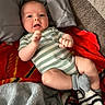 Liam joined the competition — help win amazing prizes! baby, infant, child, portrait, lying_down, smiling, wide_eyed, fists, striped_onesie, striped_socks, blanket, red_blanket, gray_blanket, pillows, couch, indoor, cozy, close_up, casual, family_photo
