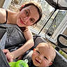 Liam is registered to the contest to win money with this photo: baby, infant, adult, woman, smiling, portrait, indoor, sunlight, patio, screened_patio, stroller, blanket, toy, green_toy, seated, family, caregiver, closeup, candid, happy