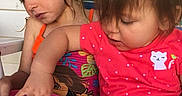 Olivia is registered to the contest to win money with this photo: children, toddler, girl, sitting, indoor, portrait, smiling, looking_down, pink_clothing, red_shirt, bowl, hand, snack_time, striped_chair, brown_hair, blonde_hair, family, casual, playful, close_up