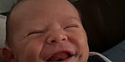 Quincy is registered to the contest to win money with this photo: baby, smile, face, infant, blanket, happy, child, indoor, person, newborn, portrait, clothing, cute, young, wrapped, head, skin, expression, sitting, cozy