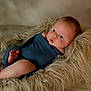 Quincy is registered to the contest to win money with this photo: baby, infant, swaddle, blue_cloth, fluffy_rug, fur_texture, curious_expression, chubby_cheeks, indoor, soft_lighting, portrait, newborn, cute, child, lying_down, floor, skin, head, small_hands, small_feet