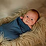 baby, infant, wrapped, blue_cloth, fur_basket, soft_texture, curious_look, face, skin, newborn, portrait, cute, cozy, lying_down, indoors, warm_lighting, head, hand, peaceful, child
