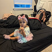 Kimaya is registered to the contest to win money with this photo: toddler, child, baby, girl, headband, bow, tutu, socks, mattress, bedroom, window, carpet, clothing, indoor, person, face, curly_hair, sitting, looking, casual