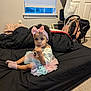 toddler, child, baby, girl, headband, bow, tutu, socks, mattress, bedroom, window, carpet, clothing, indoor, person, face, curly_hair, sitting, looking, casual