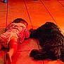 baby, barefoot, black_dog, child, cozy, cute, dog, floor, friendship, home, indoor, lying_down, orange_light, pajamas, pet, quiet, relaxing, sleeping, tile, together