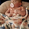 baby, sleeping, pacifier, blanket, floral, infant, cute, resting, cozy, child, soft, comfort, portrait, indoors, peaceful, pink_clothing, newborn, relaxation, cushion, face