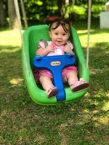 Everley is registered to the contest to win money with this photo: baby, baby_products, baby_toys, child, fun, grass, lawn, leisure, outdoor_play_equipment, person, play, playground, playset, product, public_space, recreation, riding_toy, swing, toddler