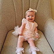 Evie is registered to the contest to win money with this photo: baby, child, smiling, dress, headband, socks, chair, indoor, cute, happy, infant, portrait, sitting, fabric, furniture, person, young, apparel, tulle, frills