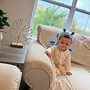 Ali is registered to the contest to win money with this photo: baby, child, infant, smile, pajamas, headband, blue, couch, blanket, living_room, window, plant, table, decor, furniture, indoors, cozy, cute, portrait, happy